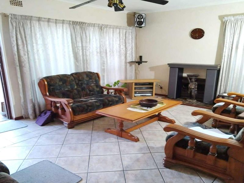 A living room featuring tiled flooring, a built-in fireplace, and a ceiling fan, offering a functional space with potential for modernization.