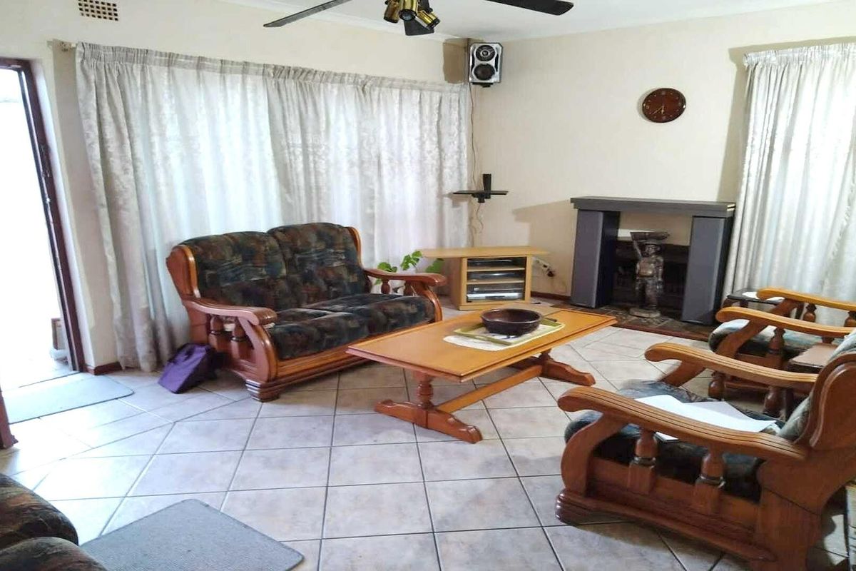 A living room featuring tiled flooring, a built-in fireplace, and a ceiling fan, offering a functional space with potential for modernization.