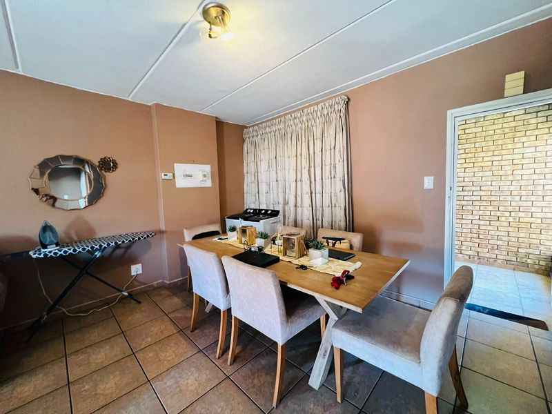 A dining area featuring tiled flooring and neutral wall tones, providing a functional space for meals with direct access to an outdoor area.