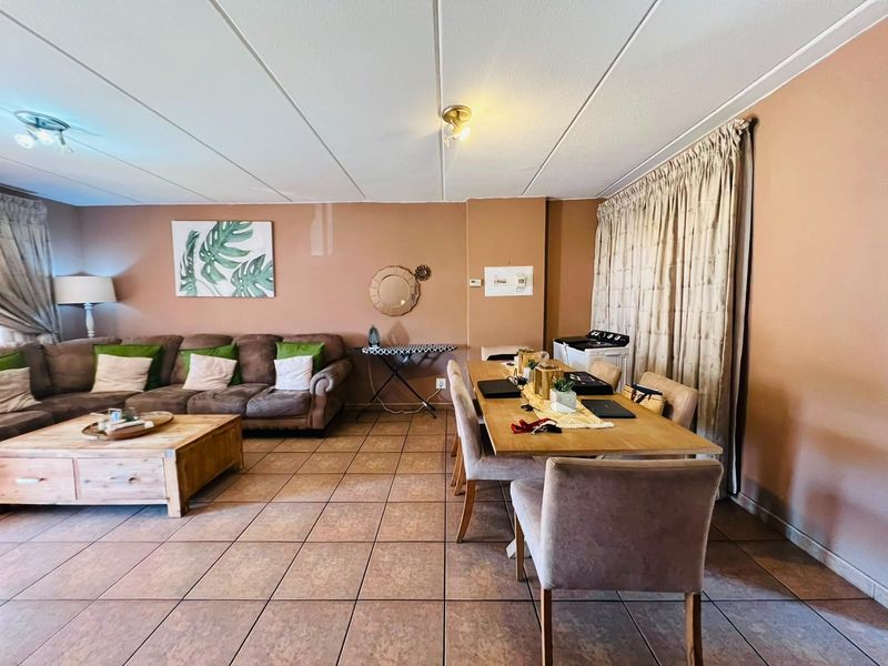 Open-plan living and dining area featuring tiled flooring and neutral wall tones, providing a functional space for relaxation and meals.