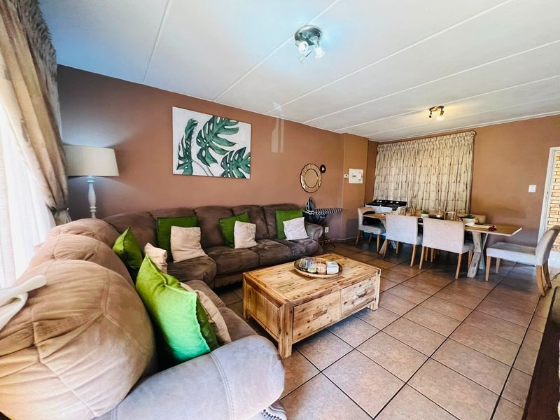 Open-plan living and dining area featuring neutral wall tones and tiled flooring, providing a functional space for relaxation and meals.