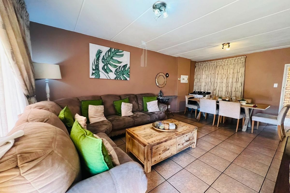 Open-plan living and dining area featuring neutral wall tones and tiled flooring, providing a functional space for relaxation and meals.