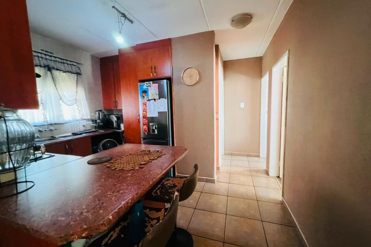 A functional kitchen featuring built-in cabinetry, a stone-look breakfast bar, and tiled flooring, providing a practical layout for daily meal preparation.