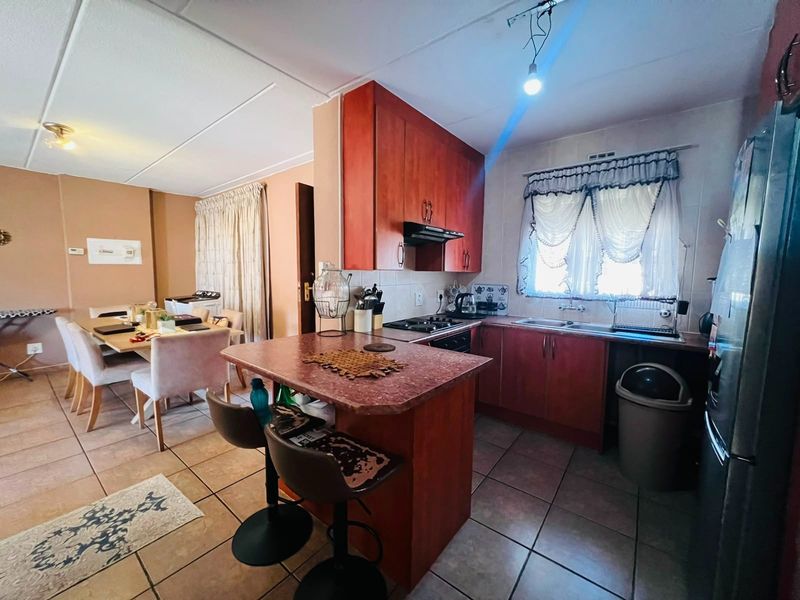 Open-plan kitchen and dining area featuring wooden cabinetry, gas hob, and tiled flooring, offering a functional layout for daily living.
