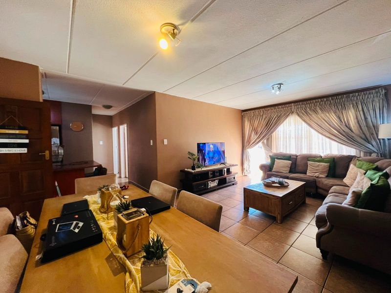 Spacious open-plan living and dining area featuring tiled flooring and direct access to a balcony through sliding doors.