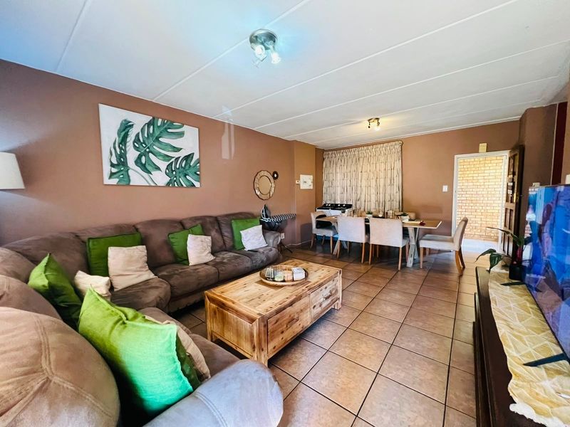 Open-plan living and dining area featuring neutral wall tones and tiled flooring, providing a functional space for relaxation and meals.