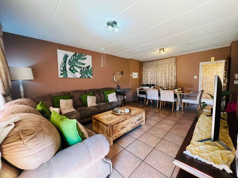 Open-plan living and dining area featuring tiled flooring and neutral wall tones, providing a functional space for relaxation and meals.