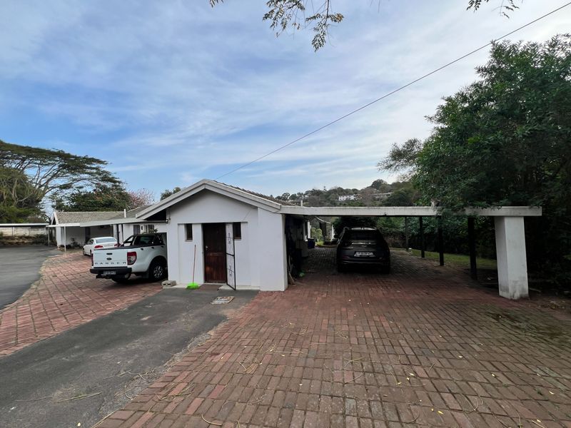 Front exterior view of the cottage featuring a brick-paved driveway and a covered carport area.