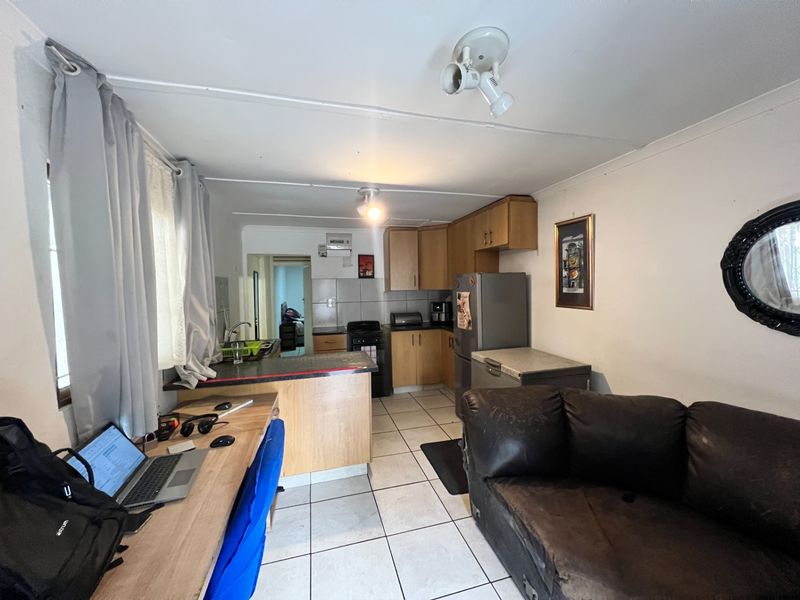 Open plan kitchen and living area featuring tiled flooring, wooden cabinetry, and a breakfast bar, offering a functional layout for daily living.