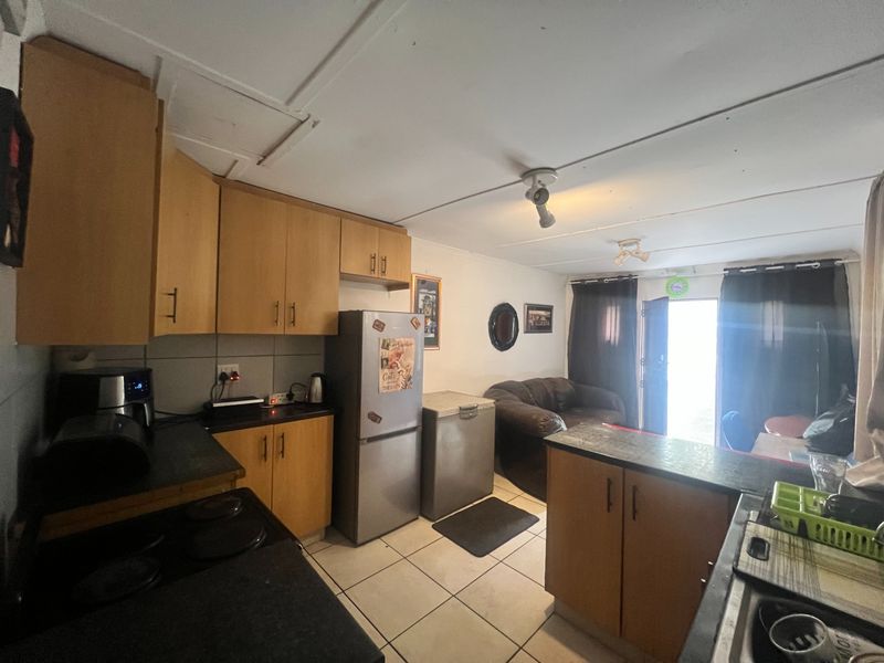 Open-plan kitchen and living area featuring wooden cabinetry, tiled flooring, and direct access to the exterior.
