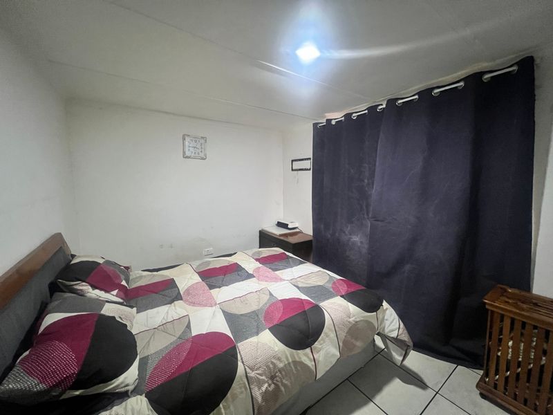 A compact bedroom featuring tiled flooring and basic lighting, currently requiring cosmetic updates to improve the overall aesthetic and finish.