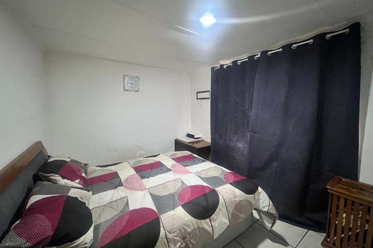A compact bedroom featuring tiled flooring and basic lighting, currently requiring cosmetic updates to improve the overall aesthetic and finish.