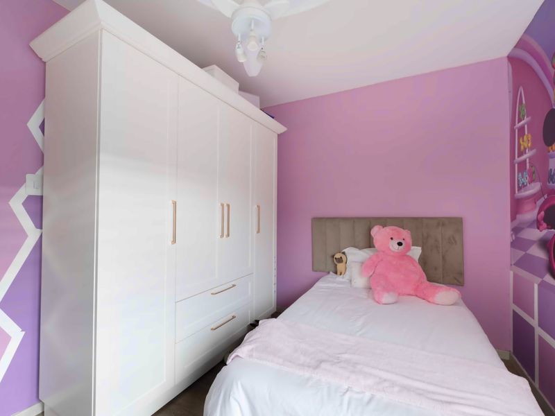 A bedroom featuring a large white built-in wardrobe and a ceiling fan, finished with vibrant purple wall paint.