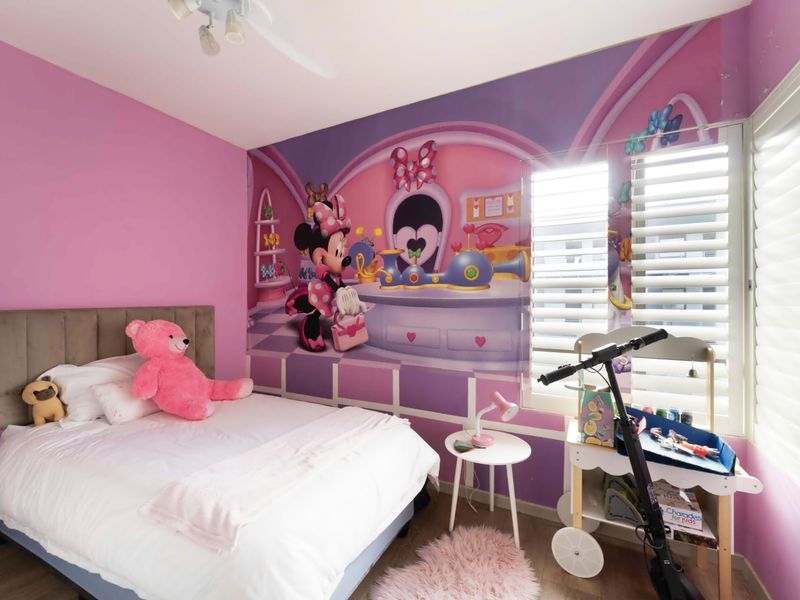 A bedroom featuring plantation shutters and a ceiling fan, currently decorated with a themed wall mural.