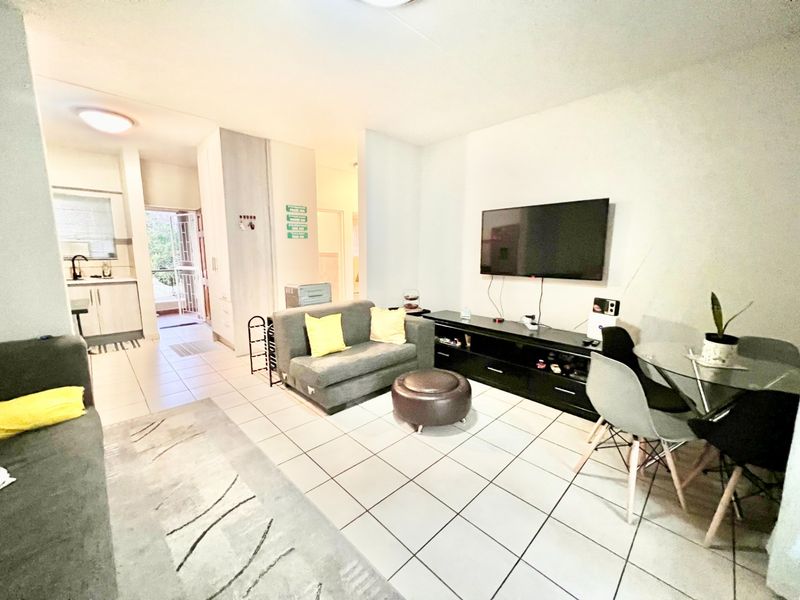 Open-plan living area featuring tiled flooring, integrated kitchen cabinetry, and a functional layout connecting the lounge and dining space.