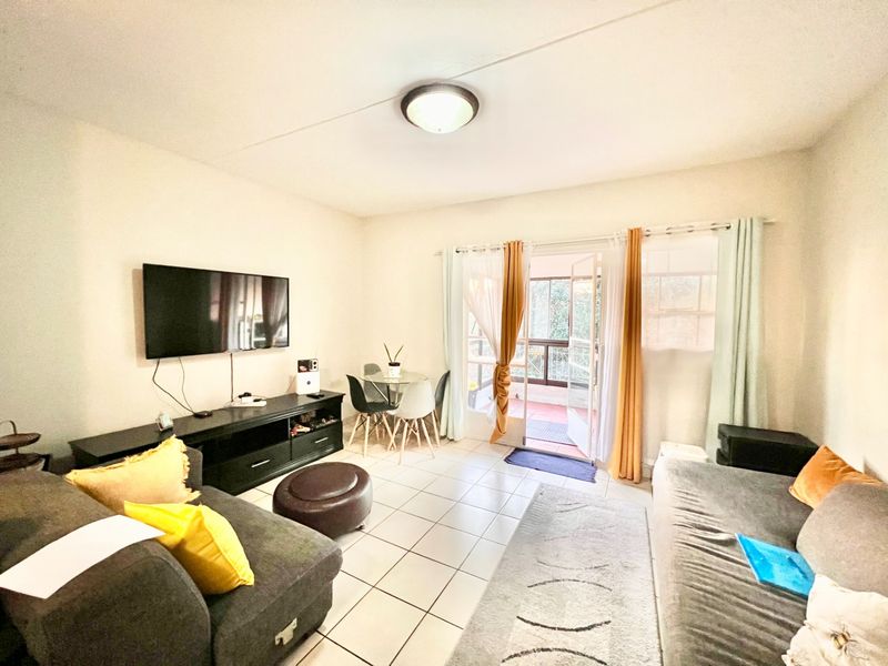 A living room featuring tiled flooring and direct access to an outdoor balcony through glass sliding doors.