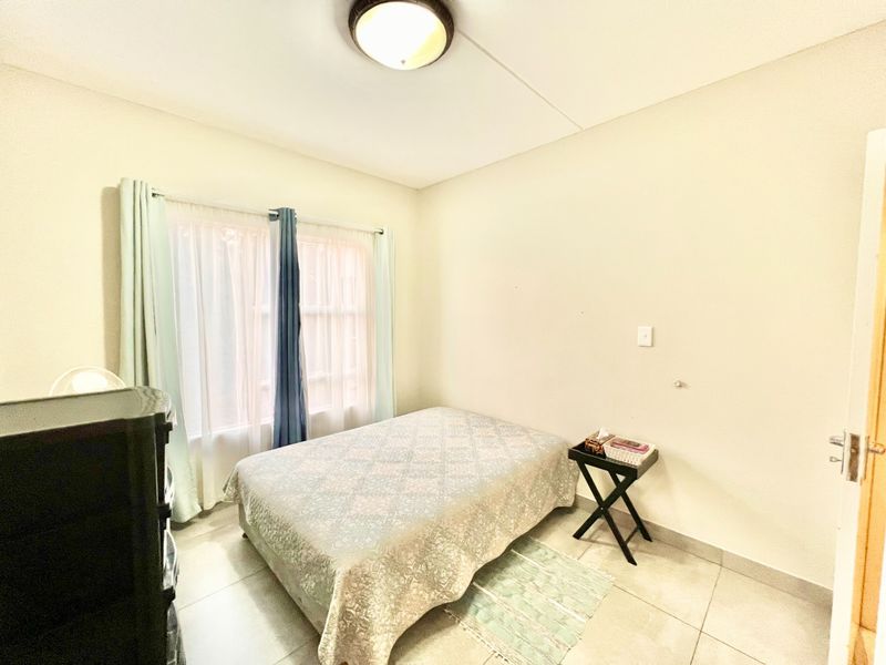 A functional bedroom featuring tiled flooring, a central ceiling light, and a window with curtains, providing a neutral space ready for personalization.