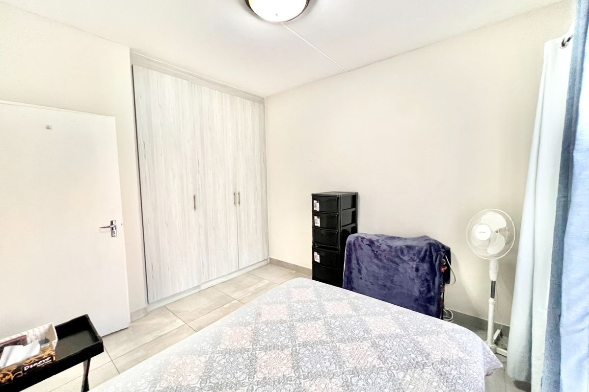A functional bedroom featuring built-in cupboards, tiled flooring, and a neutral color palette, offering a clean and practical living space.