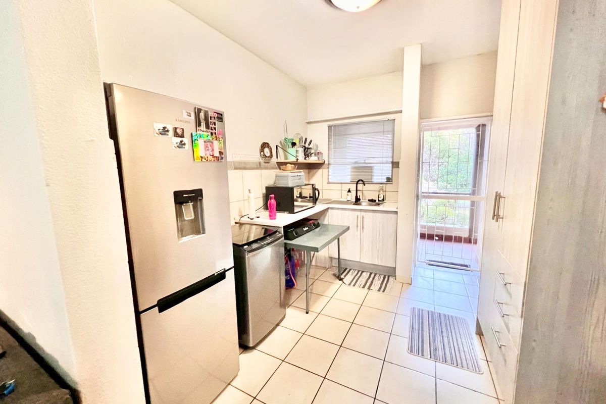 A functional kitchen featuring tiled flooring, built-in cabinetry, and direct access to an outdoor area through a security gate.