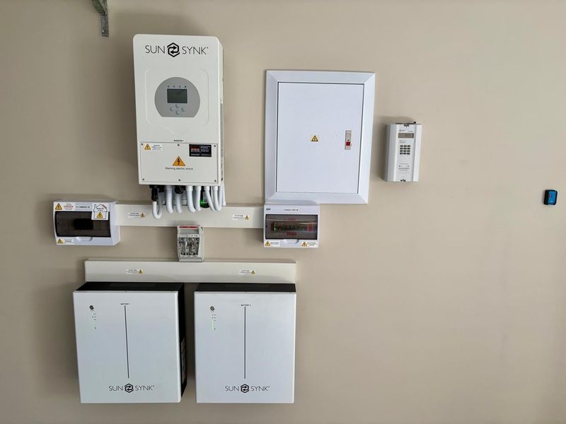 A clean and well-maintained solar power installation featuring a Sunsynk inverter and dual battery storage system with integrated electrical distribution boards.