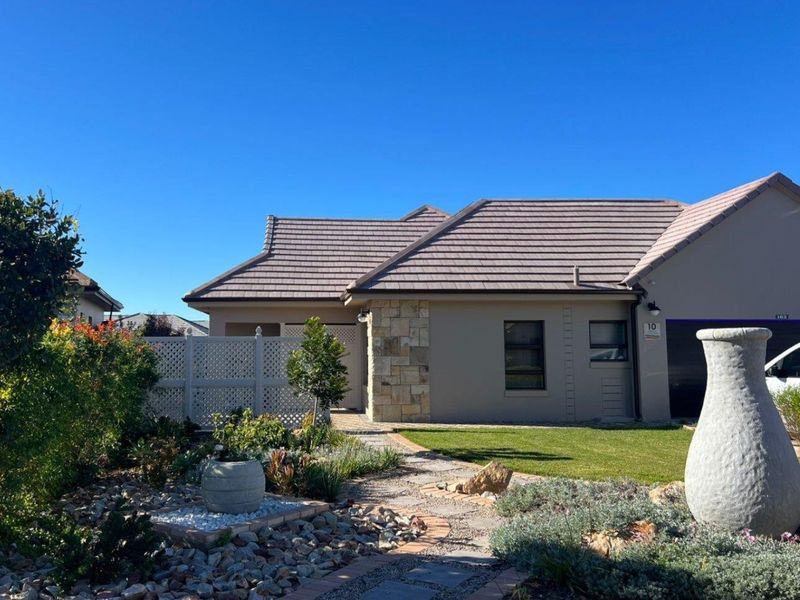 A well-maintained front exterior featuring a tiled roof, stone cladding accents, a neat landscaped garden, and a paved walkway leading to the entrance.