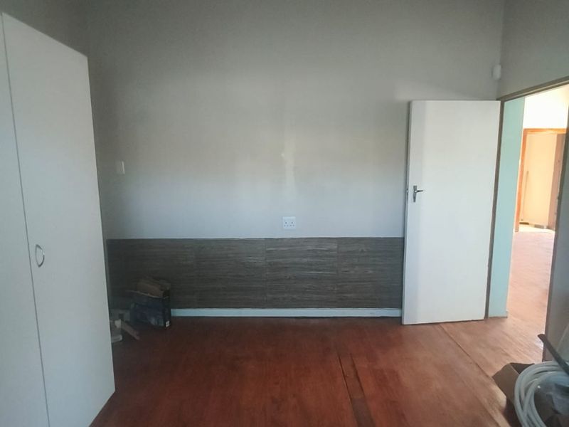 An empty bedroom featuring wooden flooring, a built-in wardrobe, and neutral wall finishes, offering a blank canvas for personalization.