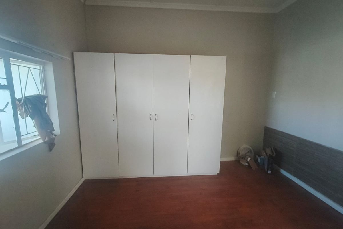 A bedroom featuring laminate flooring and white built-in cupboards, providing ample storage space.