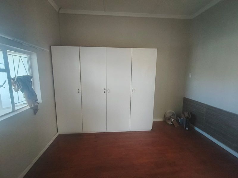 A bedroom featuring laminate flooring and white built-in cupboards, providing ample storage space.