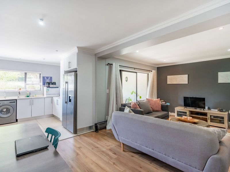 An open-plan living and kitchen area featuring modern cabinetry, laminate flooring, and a sliding door leading to an outdoor space.