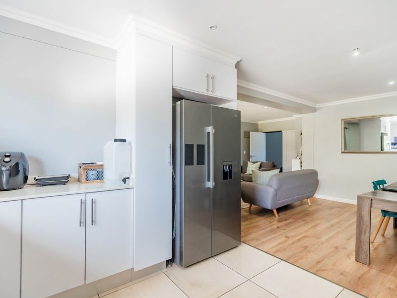 Open-plan living area featuring a modern kitchen section with built-in cabinetry, tiled and laminate flooring, and recessed lighting throughout the space.