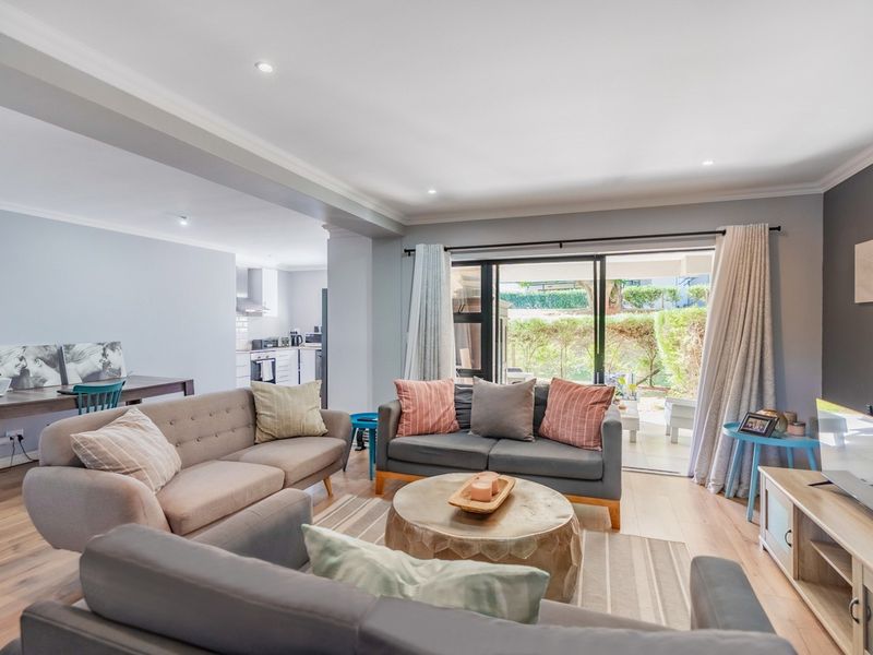 Spacious open-plan living area featuring laminate flooring, recessed lighting, and large sliding glass doors providing seamless access to the outdoor patio.