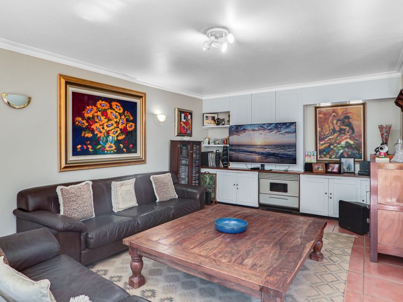 A comfortable living room featuring built-in cabinetry, tiled flooring, and classic wall sconce lighting, providing a functional and inviting space.