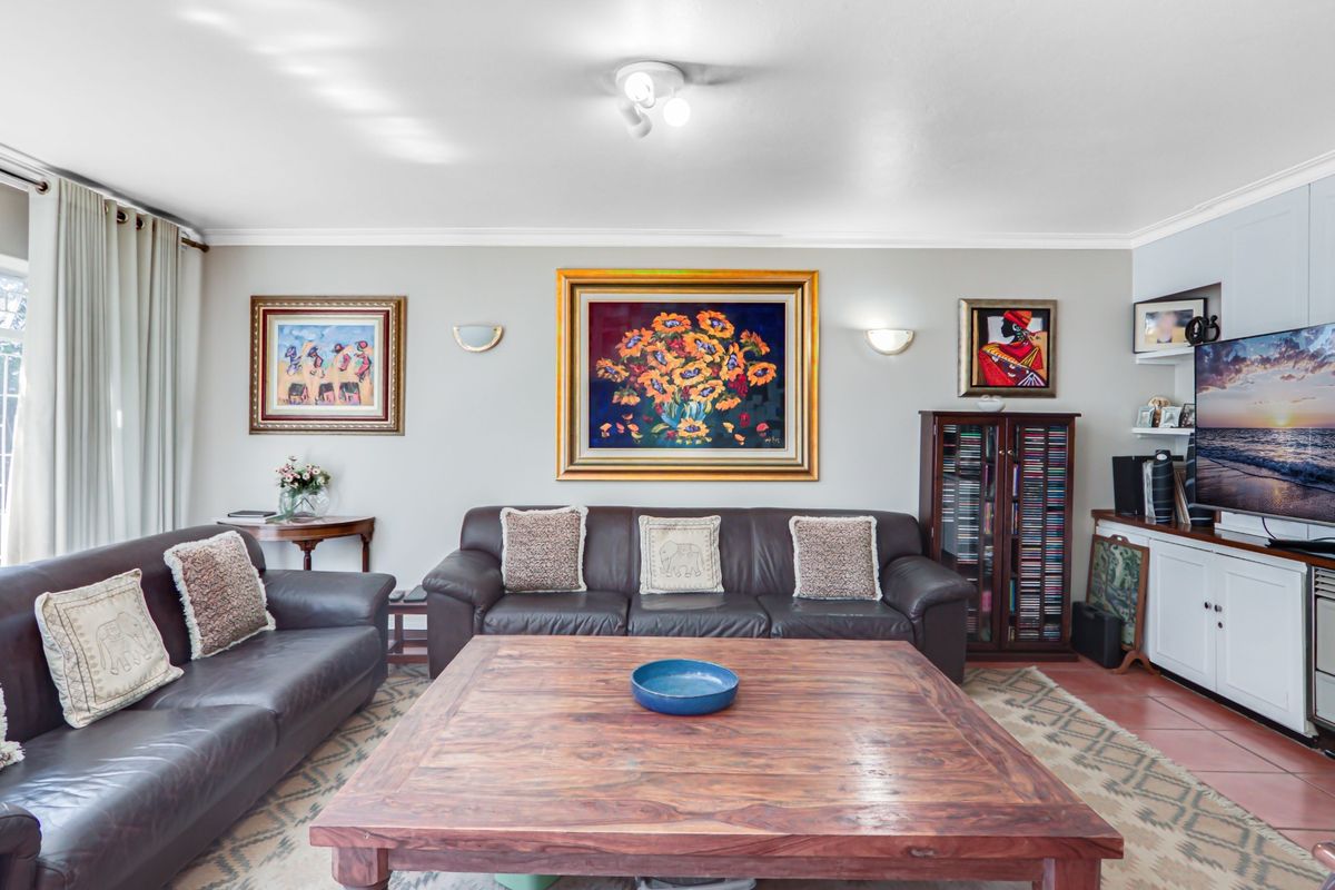 A comfortable living room featuring tiled flooring, built-in cabinetry, and wall sconce lighting, providing a functional and well-maintained space for relaxation.