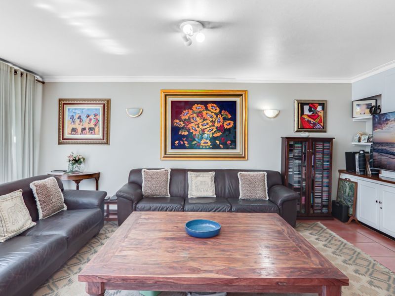 A comfortable living room featuring tiled flooring, built-in cabinetry, and wall sconce lighting, providing a functional and well-maintained space for relaxation.