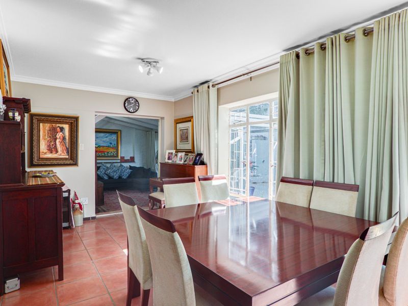 A dining room featuring terracotta floor tiles, cove cornicing, and a sliding glass door providing access to the exterior.