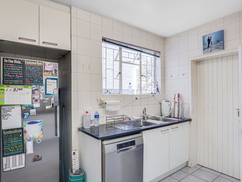 A functional kitchen featuring tiled splashbacks, a double sink, laminate countertops, and built-in cabinetry with space for a dishwasher.