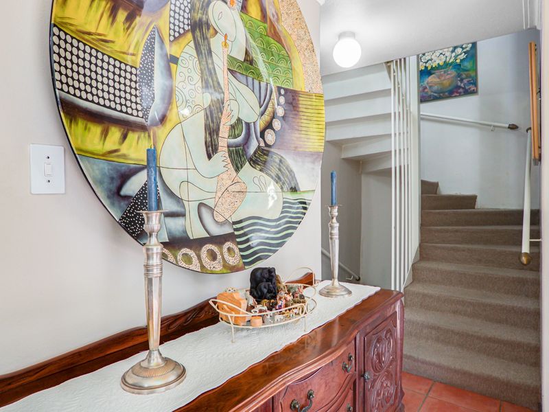 A bright hallway featuring a staircase with a handrail and tiled flooring, providing access to the upper level of the townhouse.