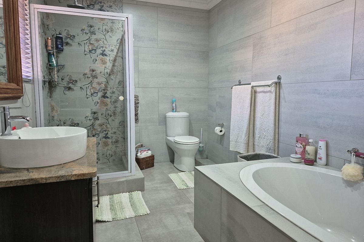 Modern bathroom featuring a glass-enclosed shower, built-in bathtub, vessel sink vanity, and neutral large-format wall and floor tiling.