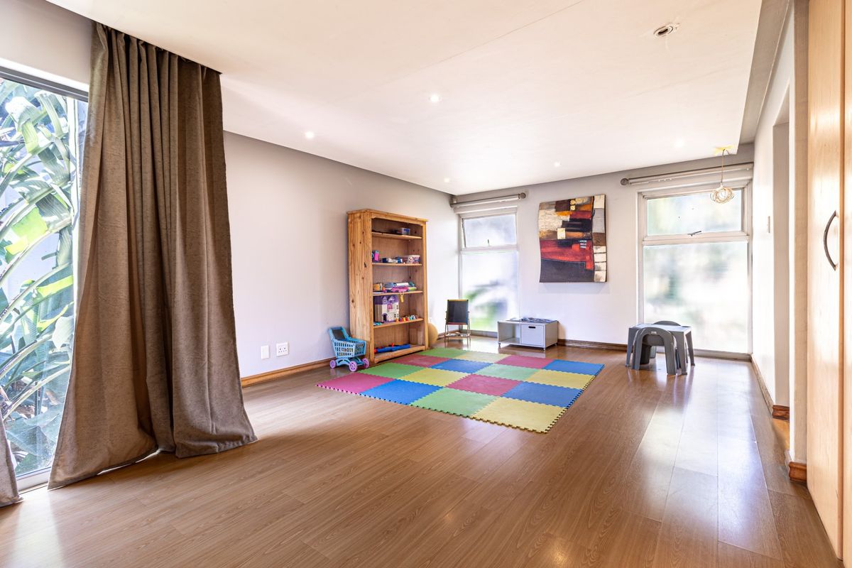 A bright and spacious living area featuring laminate flooring, recessed downlighting, and large windows that provide ample natural light.