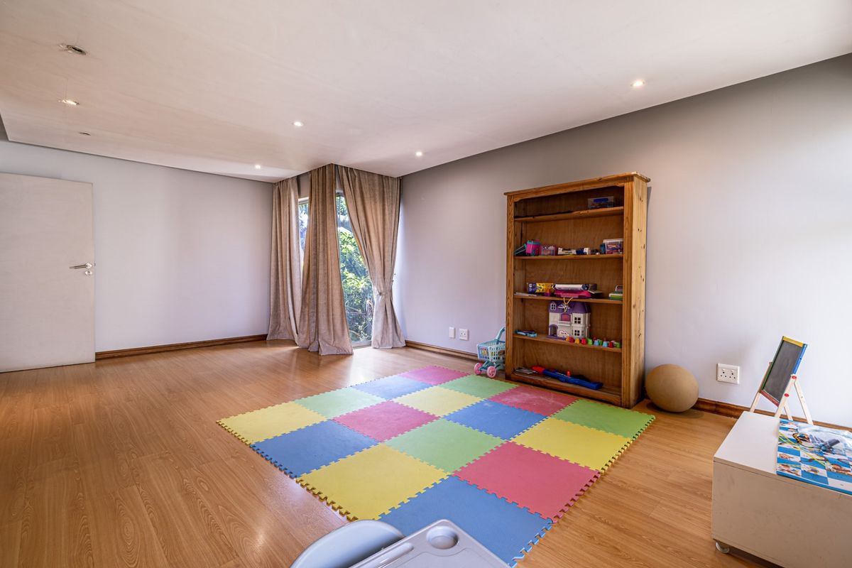 A spacious bedroom featuring laminate flooring, recessed downlights, and a sliding glass door providing natural light and garden access.