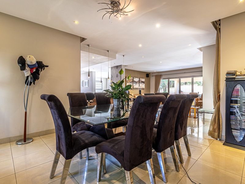 Spacious open-plan living and dining area featuring polished porcelain floor tiles, recessed downlighting, and large sliding glass doors leading to the outdoor space.
