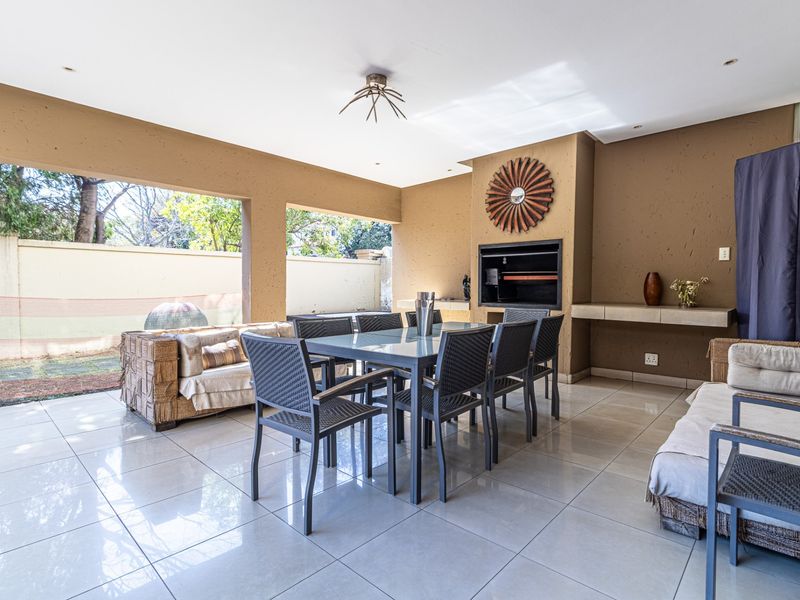 Spacious covered patio featuring a built-in braai, tiled flooring, and recessed lighting, providing an ideal space for outdoor dining and entertaining.