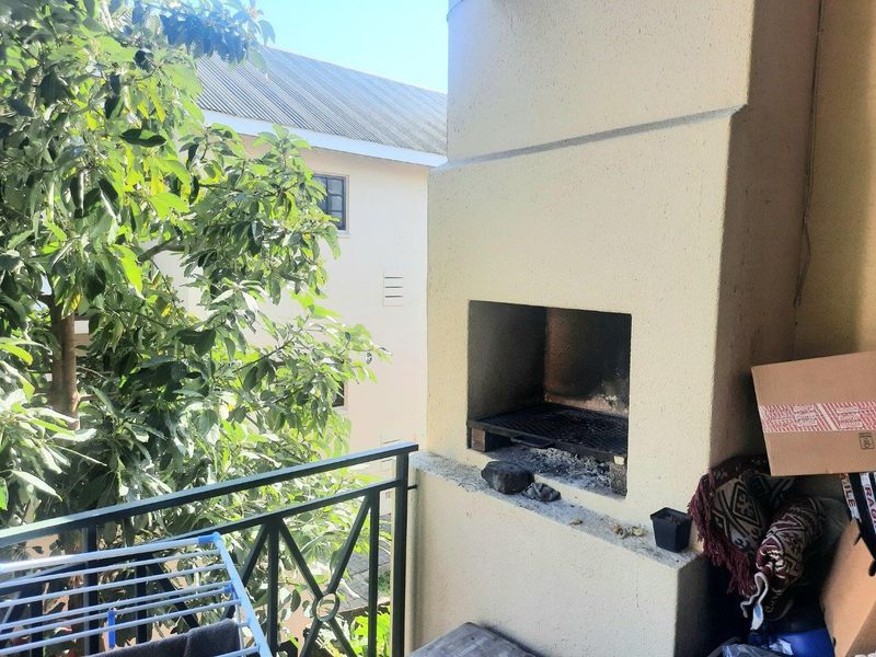 A balcony featuring a built-in braai and metal balustrade, offering an outdoor space for grilling and relaxation.