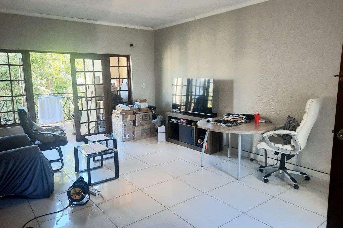 A living room featuring tiled flooring and french doors leading to an outdoor area, providing natural light and access to the balcony.