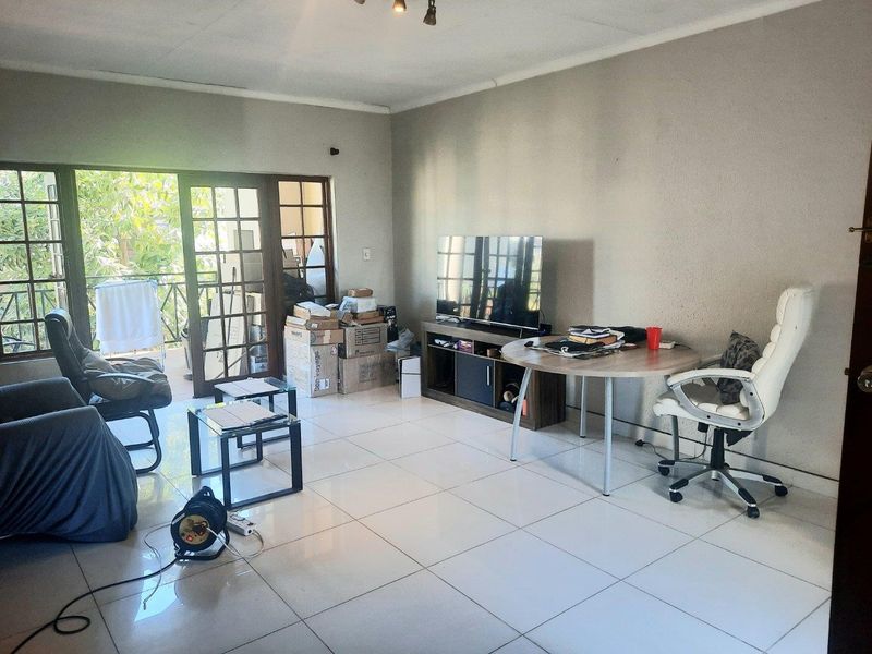 A living room featuring tiled flooring and french doors leading to an outdoor area, providing natural light and access to the balcony.