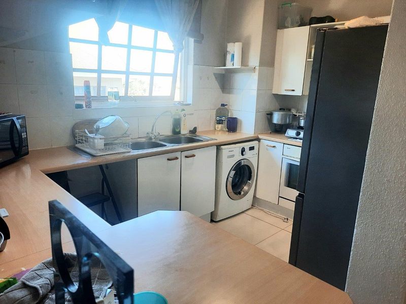 A functional kitchen featuring built-in cabinetry, laminate countertops, a double basin sink, and integrated oven, offering a practical layout with tiled flooring and backsplash.