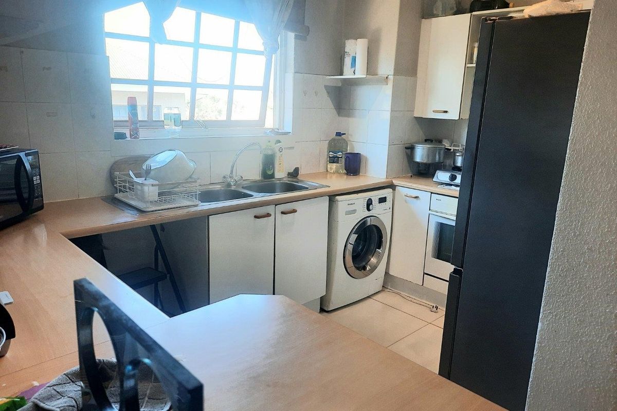 A functional kitchen featuring built-in cabinetry, laminate countertops, a double basin sink, and integrated oven, offering a practical layout with tiled flooring and backsplash.