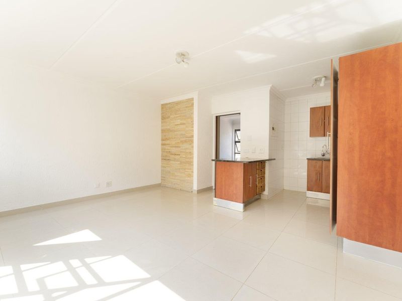 An open-plan living and kitchen area featuring tiled flooring, a stone feature wall, and functional built-in cabinetry.