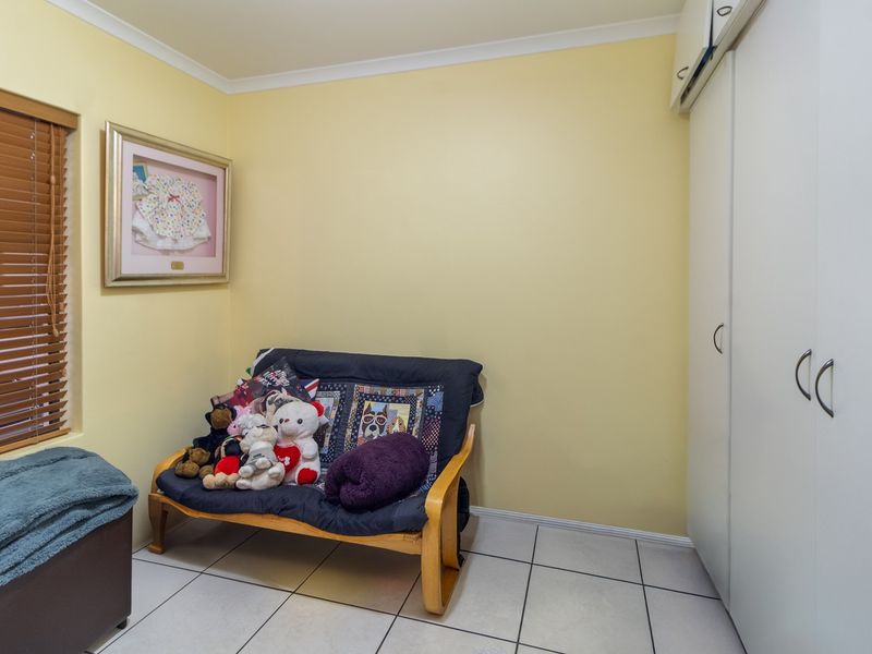A bedroom featuring tiled flooring, built-in cupboards for storage, and venetian blinds on the window.