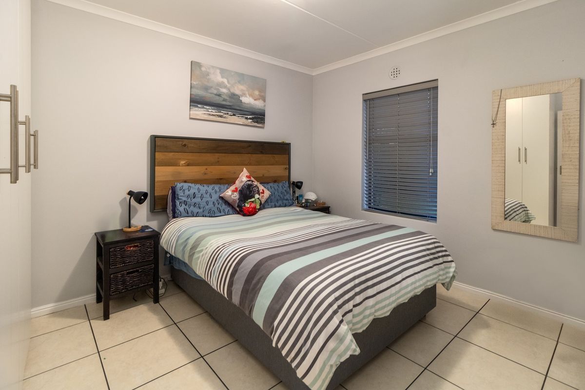 A well-maintained bedroom featuring tiled flooring, a built-in wardrobe, and venetian blinds, offering a clean and functional living space.